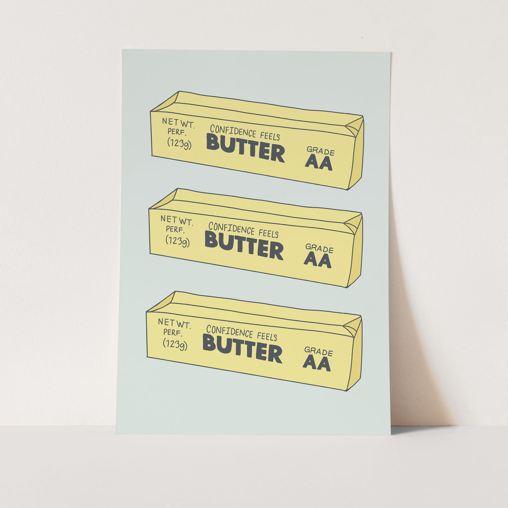 Art print for kids play kitchen that is a blue background with three butter blocks that read Confidence feels butter
