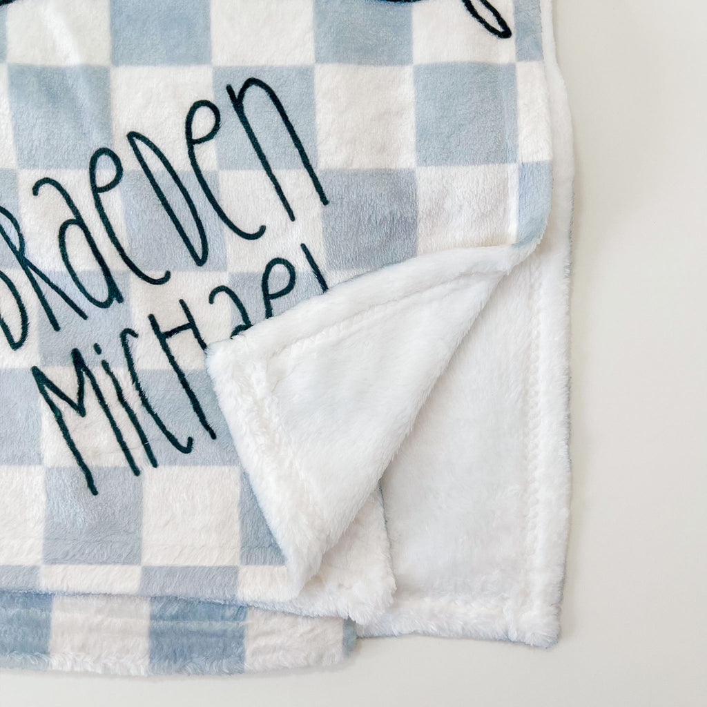 Blue and cream checkered minky baby blanket with dino spikes and babys name. personalized baby blanket